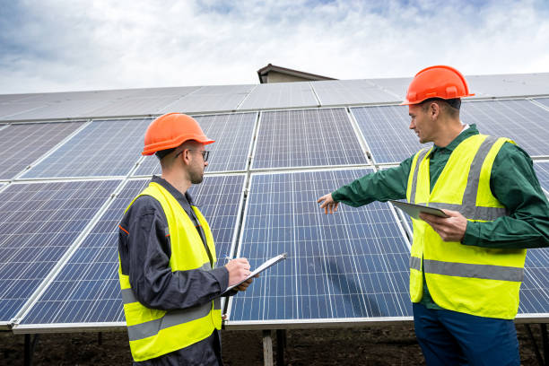 beautiful young workers in special clothes write down a plan to install solar panels. stock photo