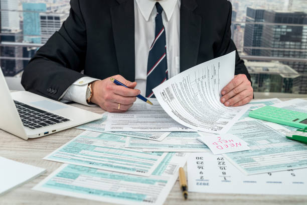 Businessman making calculation financial annual report and after fill 1040 tax form stock photo