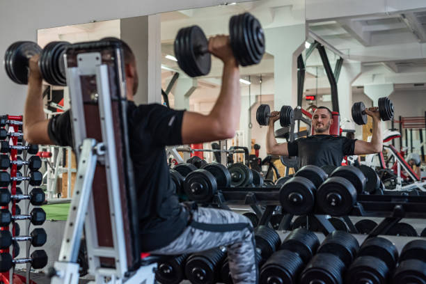 istock caucasian man doing workout with dumbbells in gym 1401714868