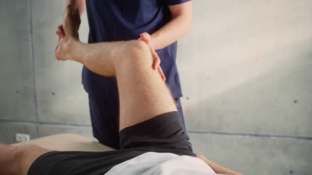 Close Up of a Young Male Athlete Undergoing Physiotherapy, Professional Sport Masseur Treating Light Muscle or Joint Injury. Musculoskeletal Pain Therapy and Rehabilitation Concept.