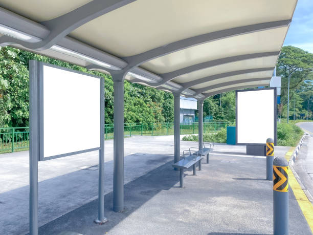 istock Blank billboard poster advertisement mockups at empty bus stop shelter by main road, greenery behind; out-of-home OOH vertical billboard media display space. 1401716528