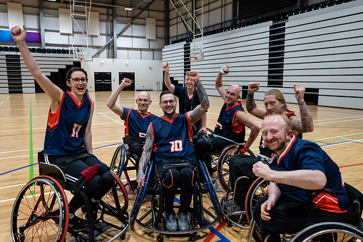 Team of wheelchair users playing basketball in the North East of England. They are wearing sports jerseys, competing against one another.