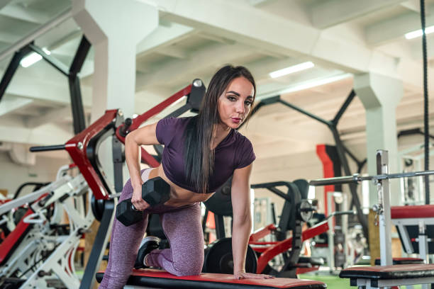 istock Young slim woman doing exercise lifting dumbbells in gym 1401716915