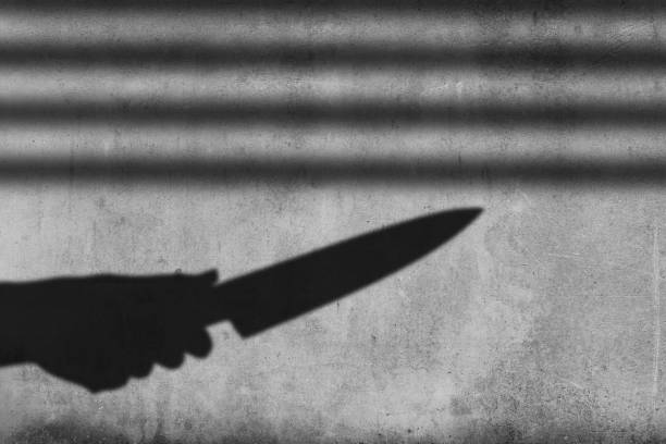istock Shadow of the hand holding a knife on wall background 1401717303