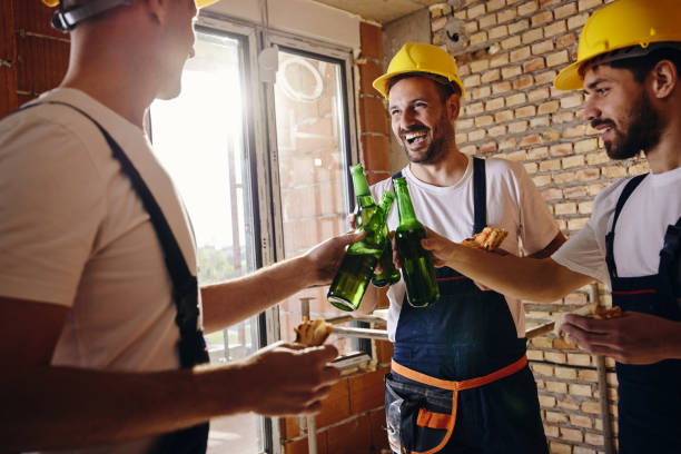 Happy manual workers toasting on a break at construction site. Happy workers toasting with beer during lunch break at construction site. construction lunch break stock pictures, royalty-free photos & images