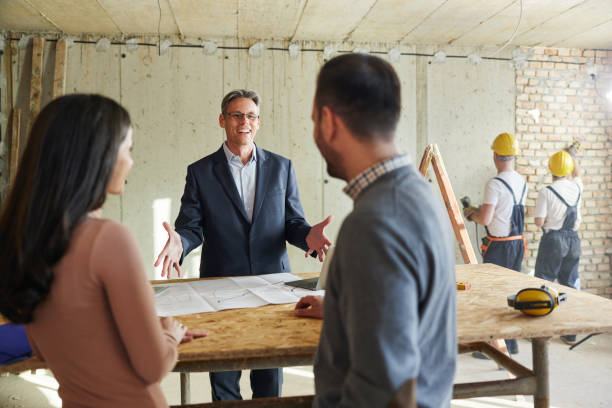 istock Happy agent talking to a couple at construction site. 1401717656
