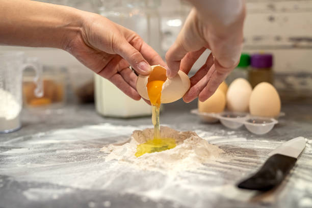 istock breaking eggs with women's hands into flour to make dough for cakes. 1401717680