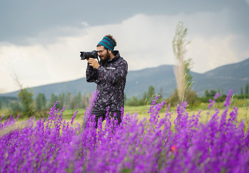 Male photographer taking landscape pictures on the field in nature