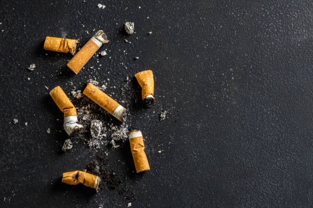 Cigarette butt on floor, environmental pollution, cigarette yellow filters stock photo