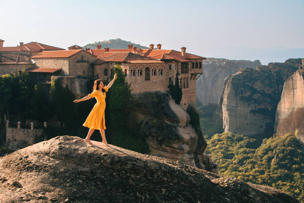 happy woman in yellow dress traveler meteora monastery on the background stock photo