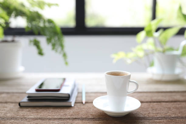 istock Ceramic white coffee cup and notebook and phone with plant pot on wooden table 1401722919