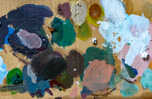 An impromptu cardboard artists pallete.  It has acrylic and oil paints of various colours on the palette.