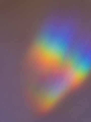 Diffracted rainbow pattern on a residential indoor wall, giving a surreal rainbow pattern for use as a background.