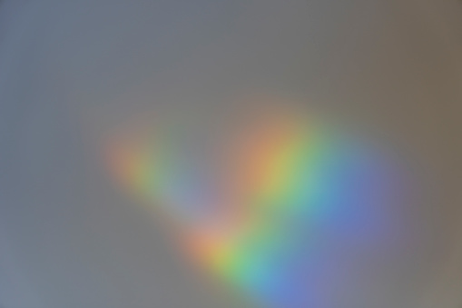 Diffracted rainbow pattern on a residential indoor wall, giving a surreal rainbow pattern for use as a background.