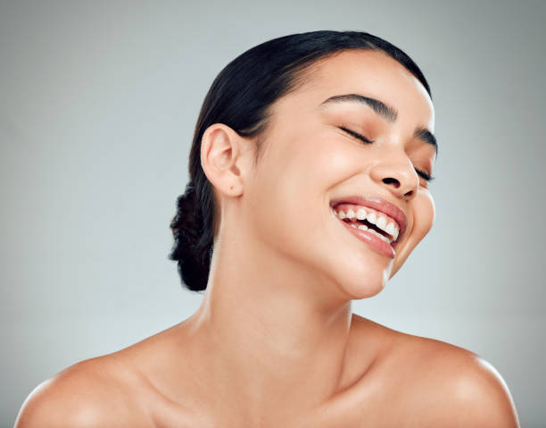 istock A beautiful young mixed race woman with glowing skin posing against grey copyspace background. Hispanic woman with natural looking eyelash extensions smiling while feeling her smooth skin in a studio 1401723733