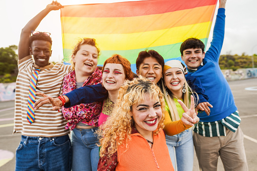 istock Young diverse people having fun holding LGBT rainbow flag outdoor - Focus on center blond girl 1401724385