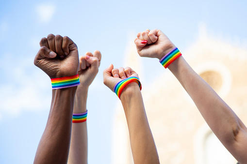 Four fists claiming gay pride rights with gay pride bracelet. LGBT and equal rights concept