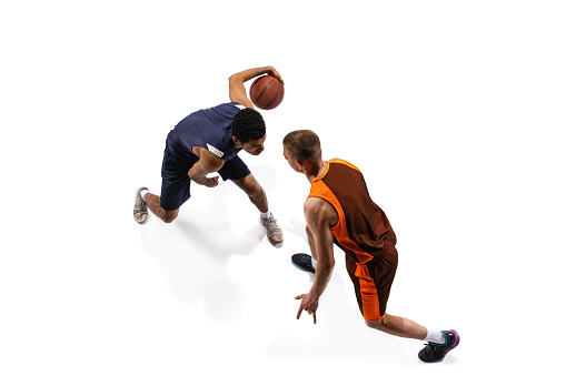 Top view portrait of two men, professional basketball players in motion, training isolated over white studio background. Defending. Concept of sport, team game, action, active lifestyle, ad