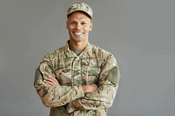 Portrait of happy African American soldier standing with arms crossed and looking at camera. Copy space.