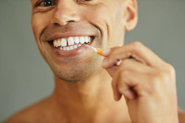 istock Close up of black man using interdental toothbrush. 1401729079