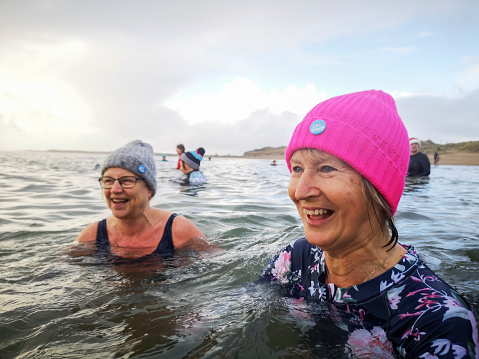 Burry Port, Wales, UK: December 26, 2021: A group of mature female friends swimming in the sea. The Bluetits Chill Swimmers Ltd is a social enterprise committed to empowering our inclusive community of outdoor dippers.