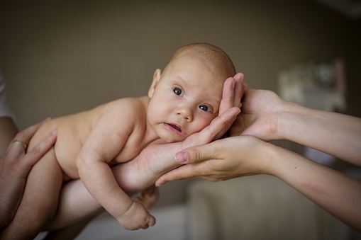 little baby boy lying on father and mother hands.