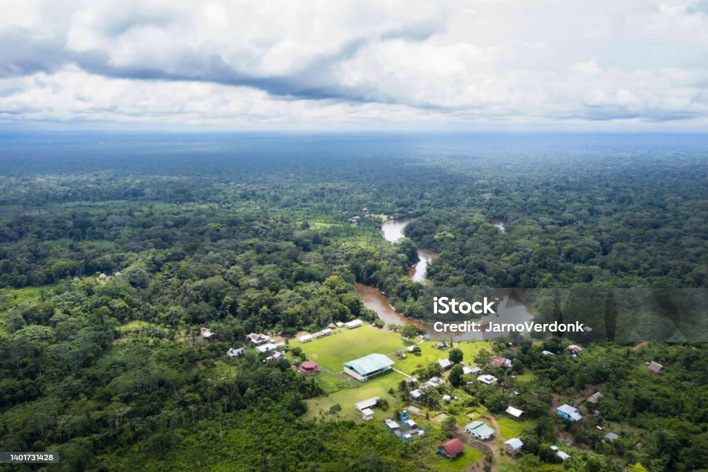 Beautiful background of an indigenous community in the Amazon rainforest: a tropical river is curving through a tropica forest with houses in the foreground Beautiful background of an indigenous community in the Amazon rainforest Community Stock Photo