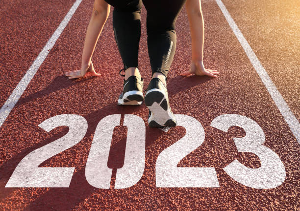 athletics track engraved with the year 2023 Rear view of a woman preparing to start on an athletics track engraved with the year 2023 2023 photos stock pictures, royalty-free photos & images