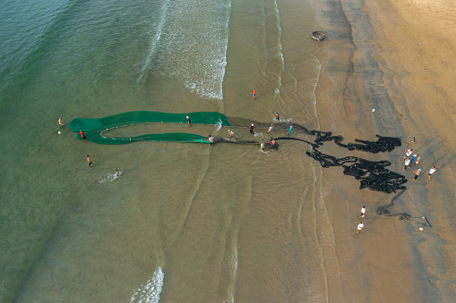 Drone view of fishermen pulling fishing net and collecting fishes by the beach, Da Nang city, Quang Nam Da Nang province, central Vietnam