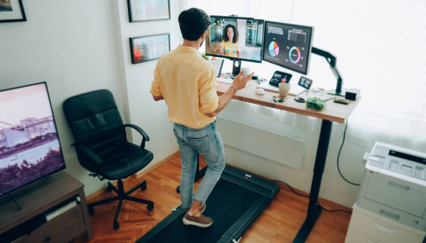 Man at standing desk home office talking on business video call stock photo