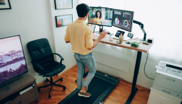 Man at standing desk home office talking on business video call Man working from home at standing desk working from home stock pictures, royalty-free photos & images