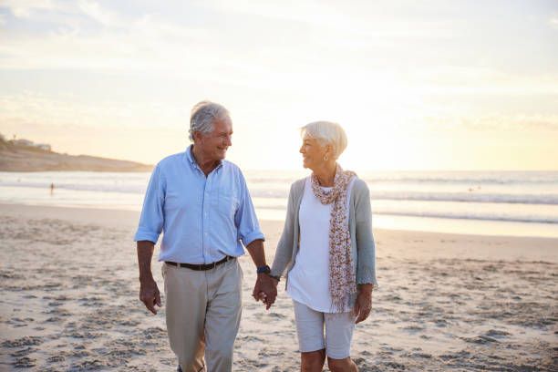 istock Loving senior holding hands while walking on a beach at sunset 1401738739