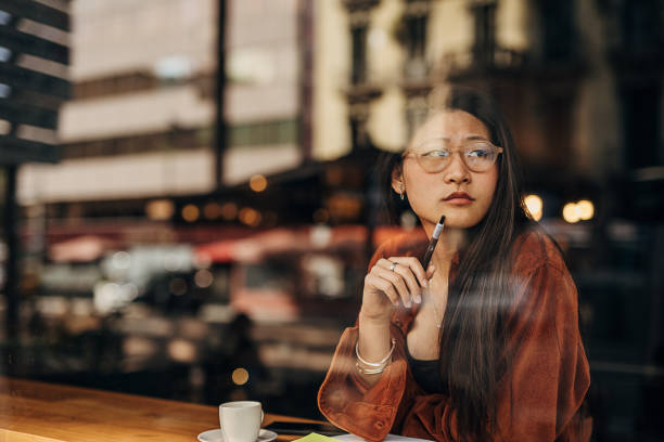 Asian woman sitting in the cafe and writing notes while being on the coffee break