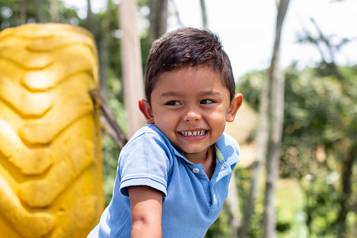 Portrait of a latin boy smiling. Happy child enjoying a nice park surrounded by nature.
