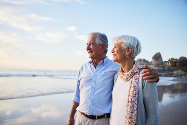 istock Smiling seniors enjoying the ocean view on a beach at sunset 1401740132