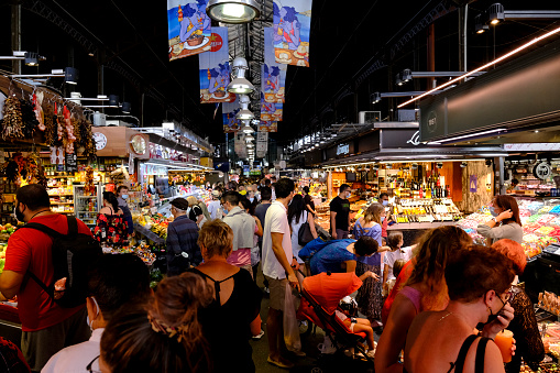 Tourists and pedestrians fill an aisle between food stalls inside Boqueria market in Barcelona, Spain on October 2, 2021.