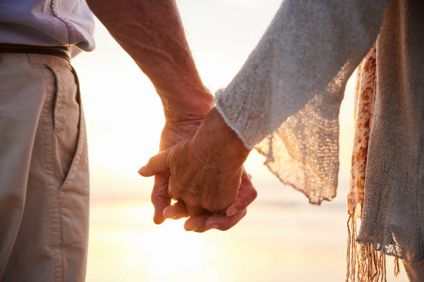 istock Senior couple holding hands together on a beach at sunset 1401741630