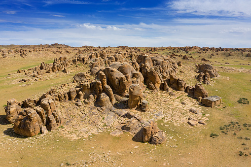 Aerial view at rock formations and stacked stones on granite hilltops. Baga Gazriin Chuluu, Gobi desert, Mongolia.
