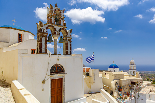 The bell tower on Santorini streets under blue sky during sunny day.