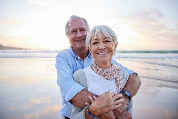 istock Loving senior couple smiling while standing together on a beach at sunset 1401742919
