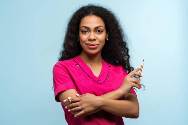 Portrait Non-Caucasian Skinned Woman Master Beautician of Eyebrow Tattooing on Blue Background. Eyebrow Tattoo Artist Master Holds Tattoo Tool Maniple for Microblading. Training in Permanent Makeup