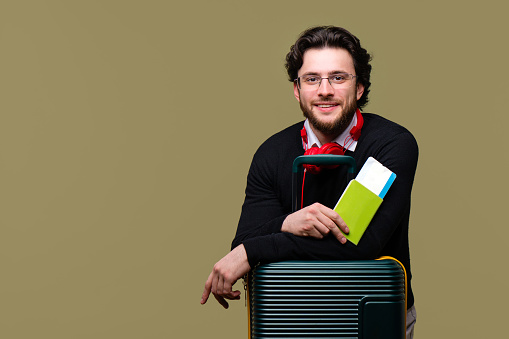 Bearded Man Traveler Tourist holds Passport and Airline Boarding Pass Ticket. Hipster in Casual Outfit Travels on Vacation Trip with Suitcase. Airline Passenger Transportation. Air Flight Journey