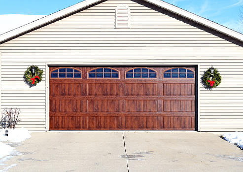 Two wreaths on either side of wooden garage door.