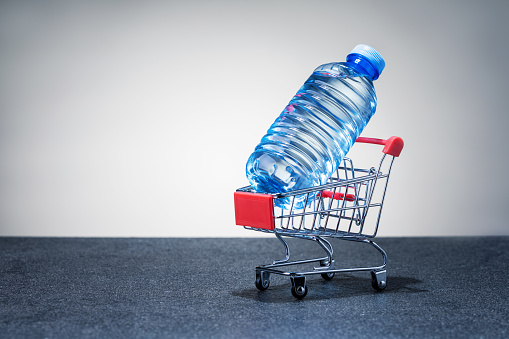 Shopping cart with bottle of water. copy space. Concept of water delivery.