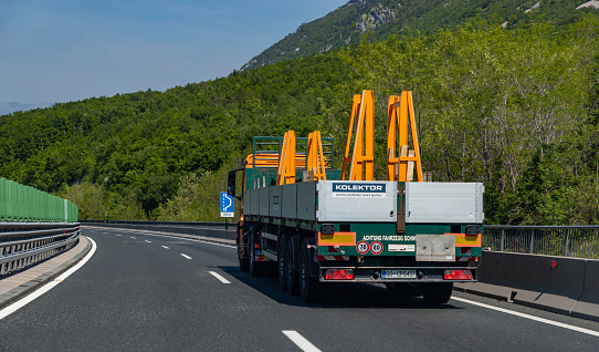 Ljubljana, Slovenia - May 11, 2022: A picture of a truck carrying construction equipment on a Slovenian highway.