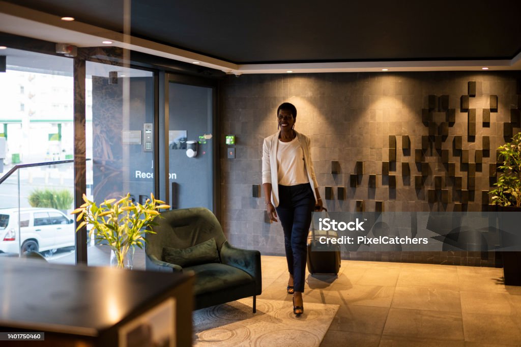 Wide shot businesswoman enters luxury hotel lobby African businesswoman checking in at luxury hotel reception desk Hotel Stock Photo