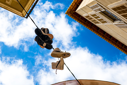 Photography from below of shoes hanging down from a telephone wire as a tradition of organized crime called shoe tossing, also known as shoefiti, a ceremony in the streets of Palma de Mallorca.
