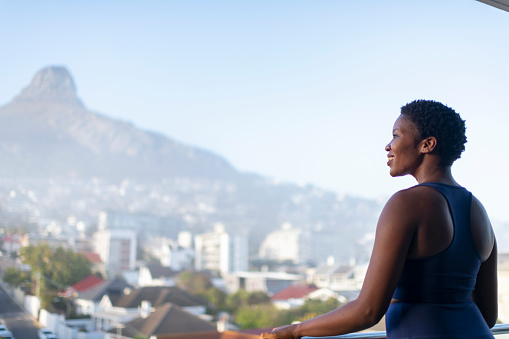 Woman looks out at morning city view with mountain peak