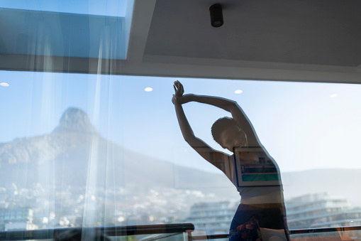 Woman stretches early morning reflected with view in window