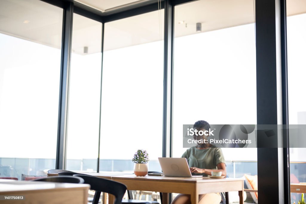 Wide shot with copy space woman using laptop in cafe Using Laptop Stock Photo